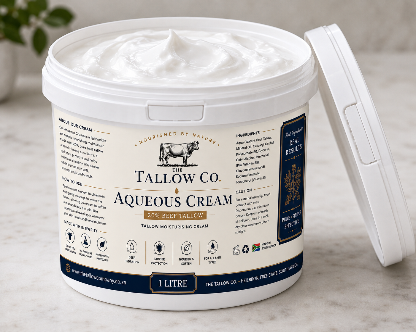 A 1 litre tub of Tallow Co. Aqueous Cream 20% beef tallow moisturising cream, shown with its white lid propped open on a light marble surface.